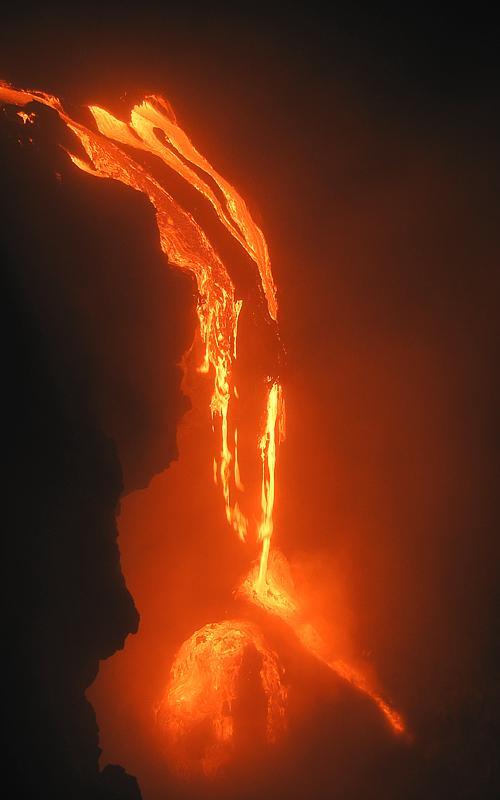 Cascade and lava falls over sea cliff 