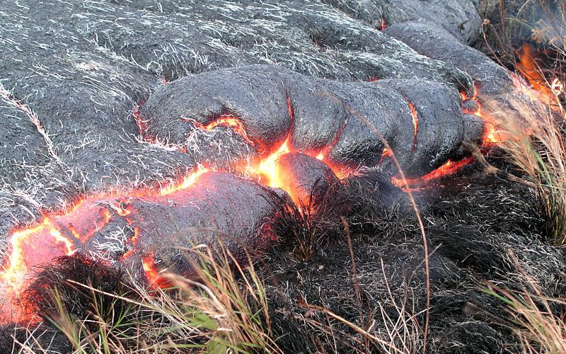 Lava slowly advancing through grassland.