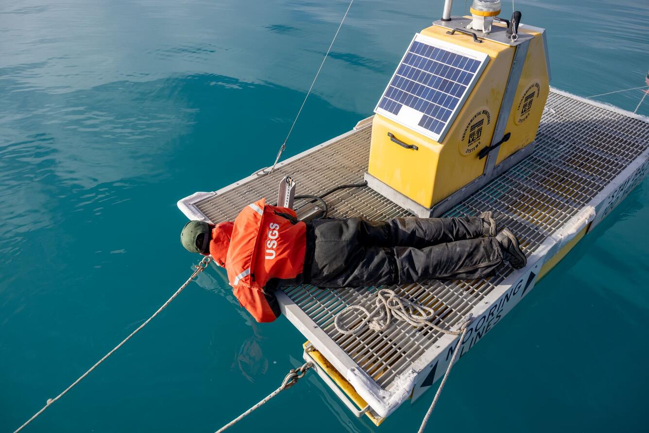 USGS hydrologist laying down on water-quality platform