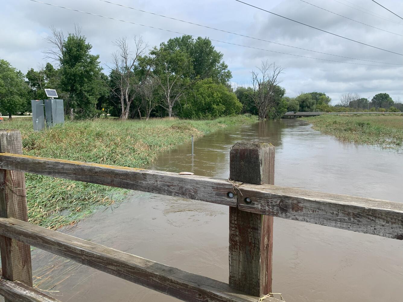 Streamgage on a grassy shoreline next to a flooded river