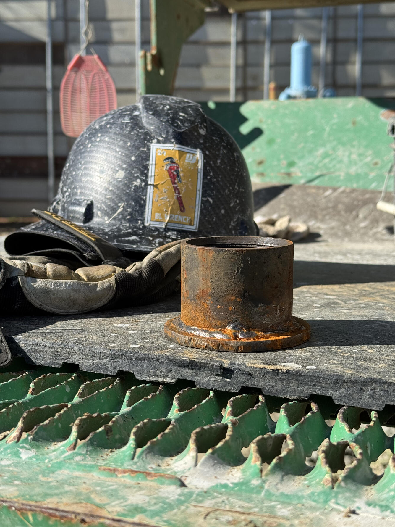 A metal endcap with a flat base which serves at the foot of an extensometer. It is about half the size of a nearby hardhat.