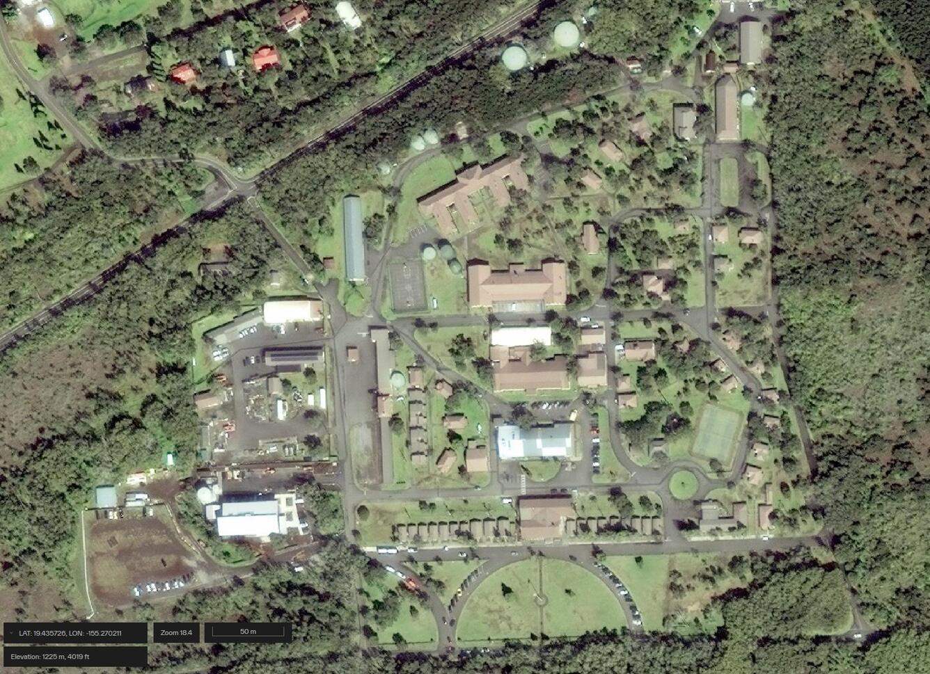 Satellite image of buildings and roads surrounded by grass and vegetation