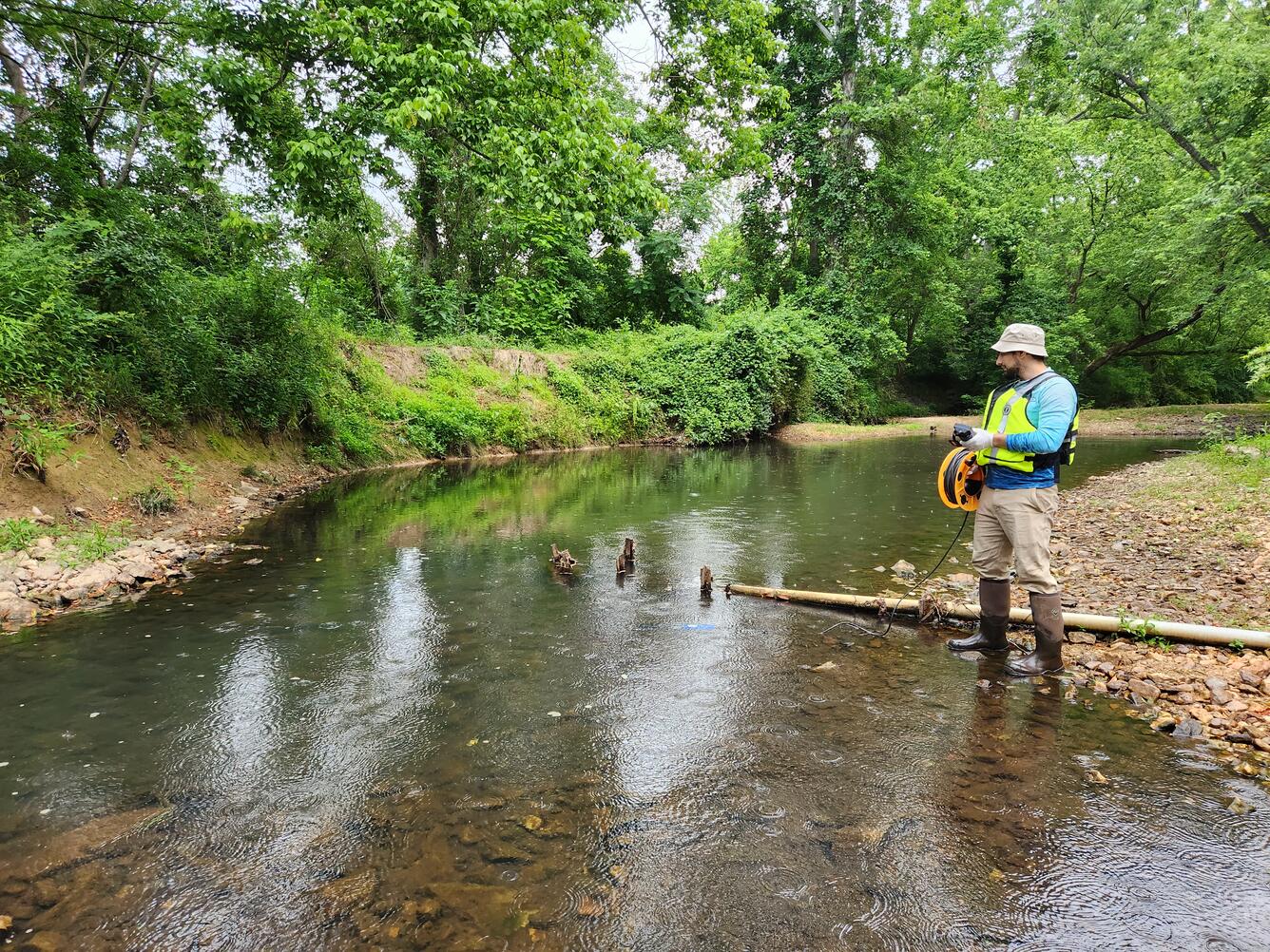 A hydrotech takes readings in a shallow urban stream using a water quality sonde.