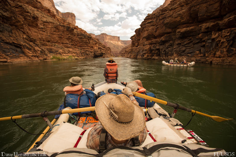 People relax on a raft floating through a calm section of the Colorado River in Grand Canyon