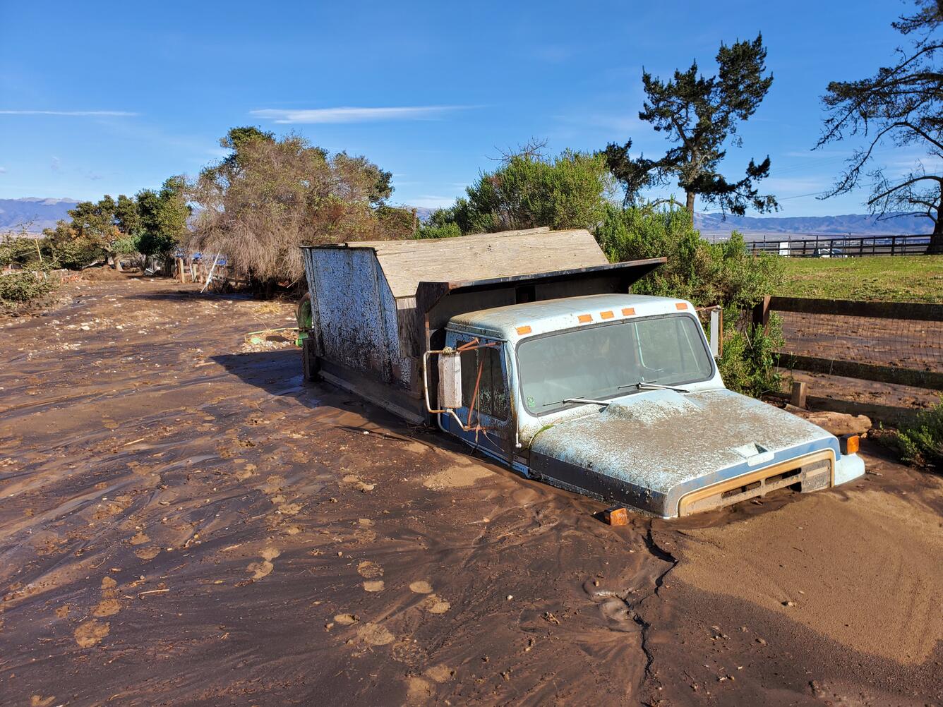 mud partially covering a fence and truck