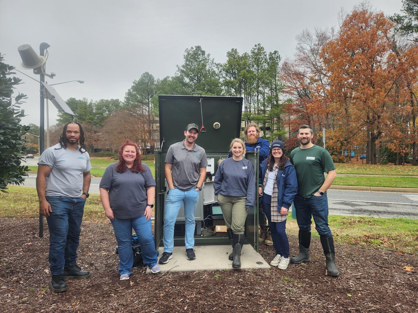 Two USGS scientists and five HRSD researchers pose for a group photo in front of a monitoring station.