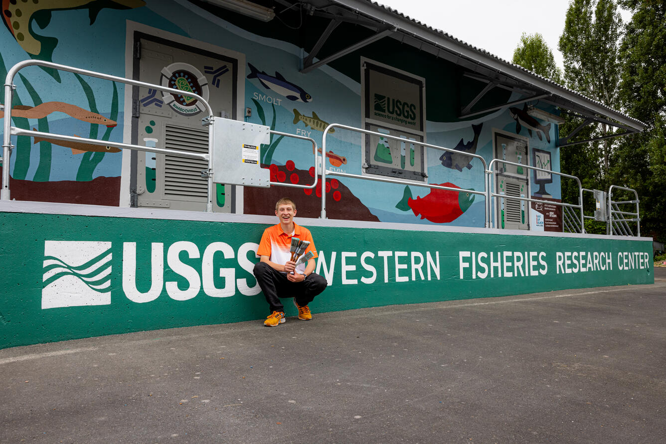 Muralist designer, Austin Picinich in front of finished mural