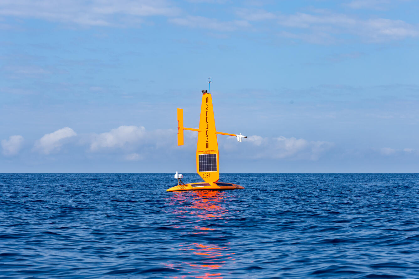 A saildrone, an orange autonomous sailing vessel, out on a lake
