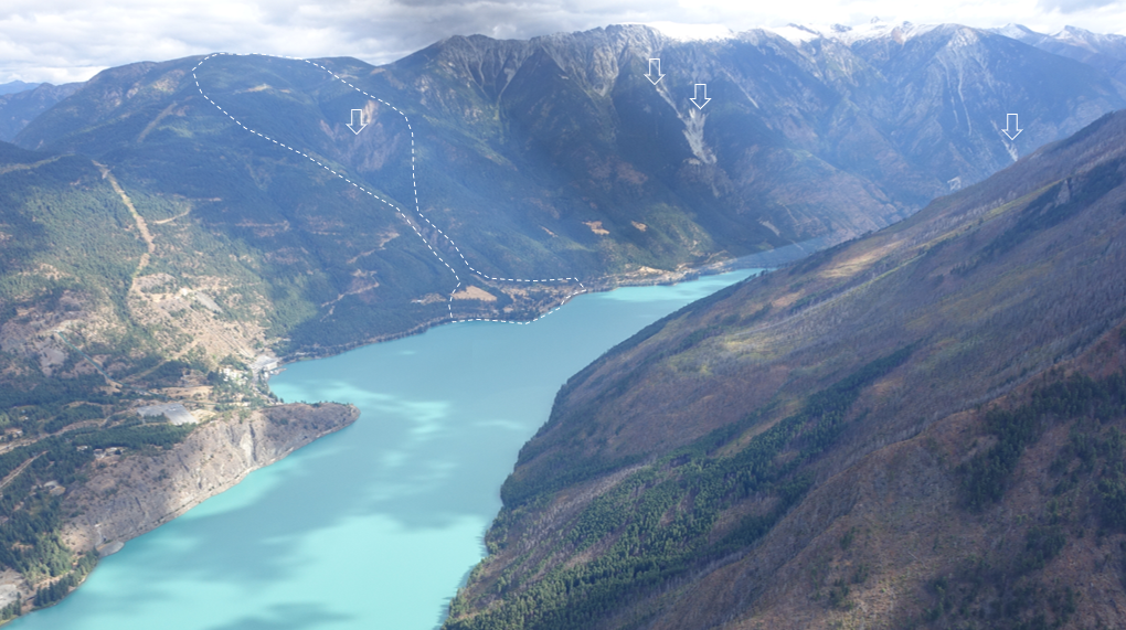 Blue lake between two mountains with white outline around landslide