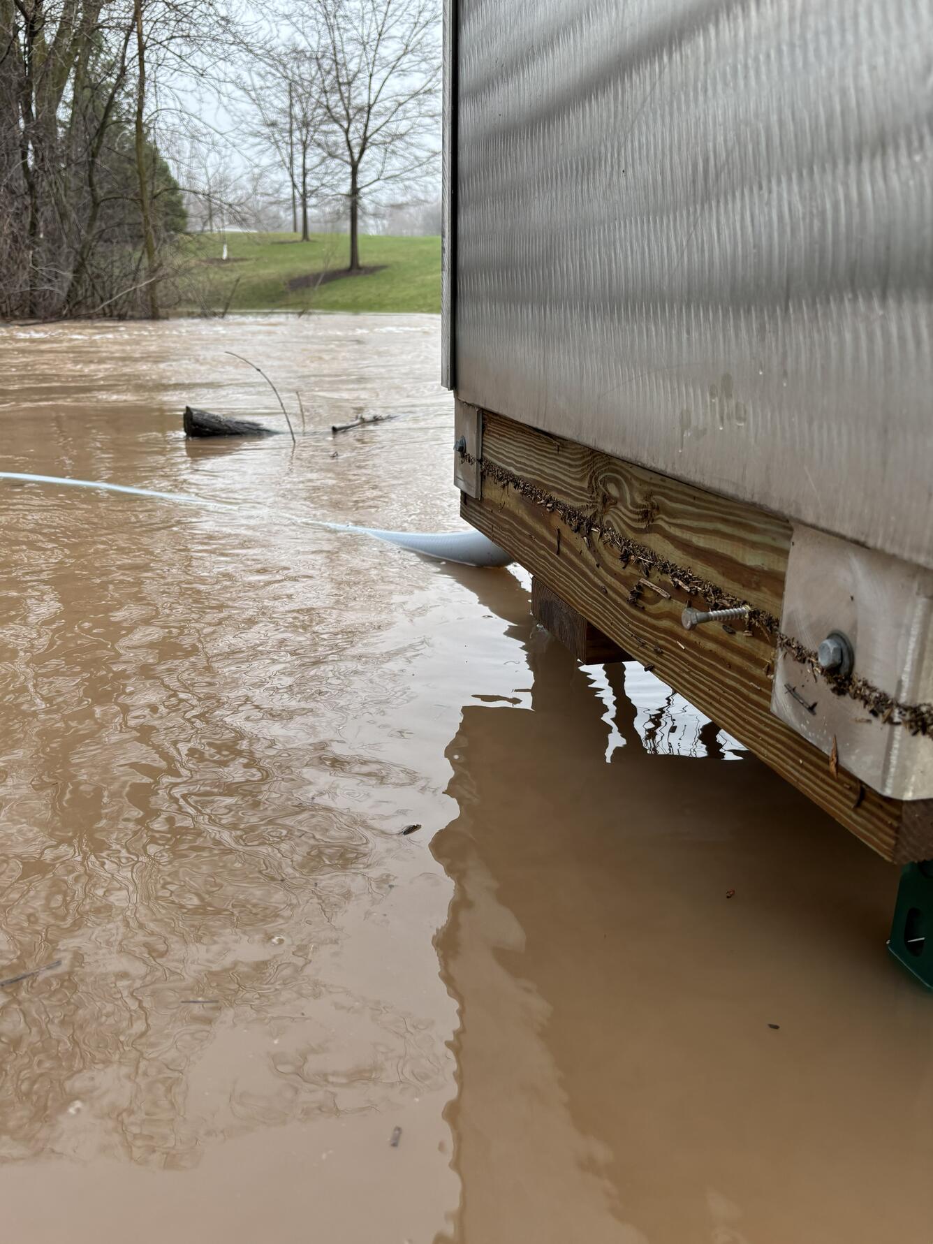 A brown flooded river flows just underneath a streamgage platform