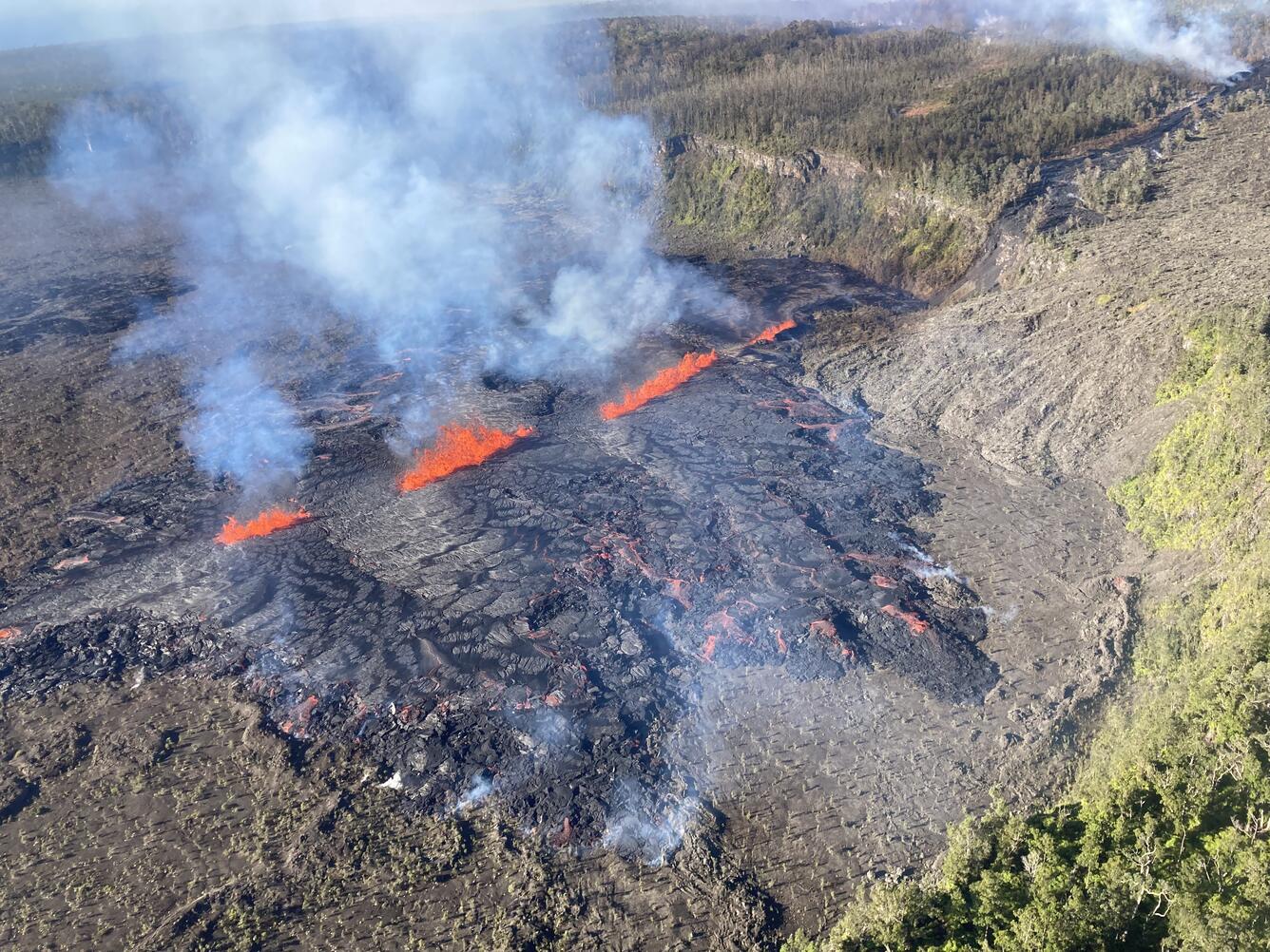 Color photograph of volcanic eruptive fissure emitting lava flows and volcanic gas