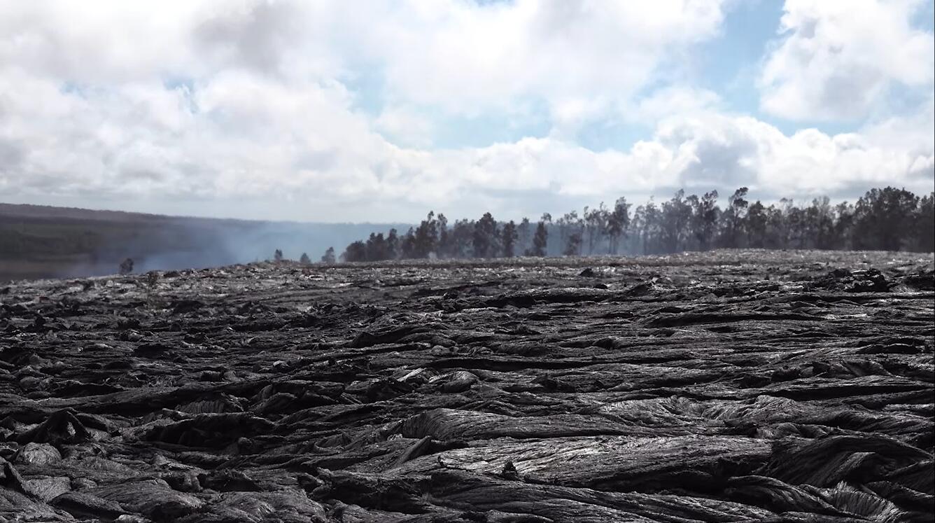 Color photograph of newly erupted lava and fume in the background