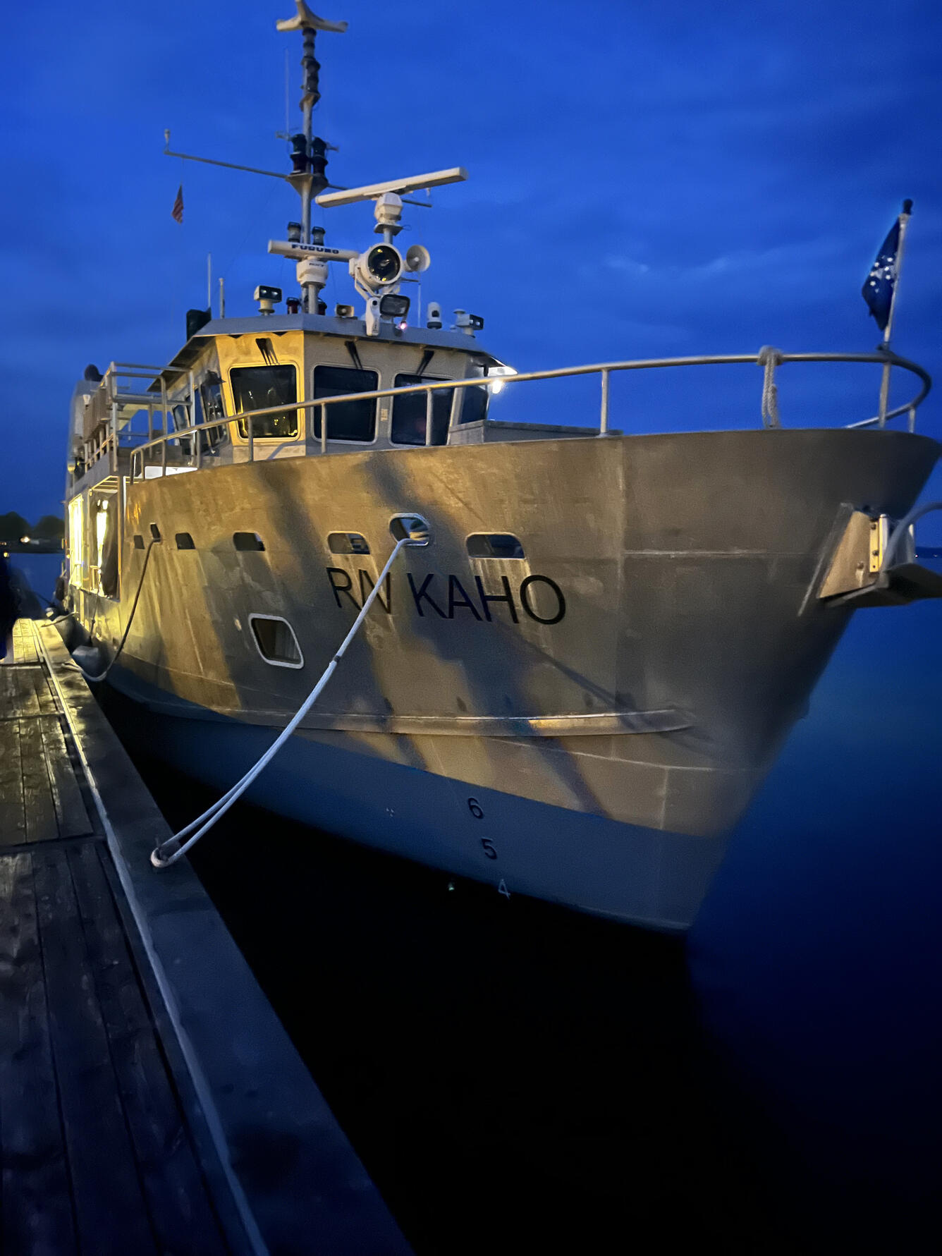 Bow of a large research vessel docked at night. R/V Kaho on the starboard side of the bow