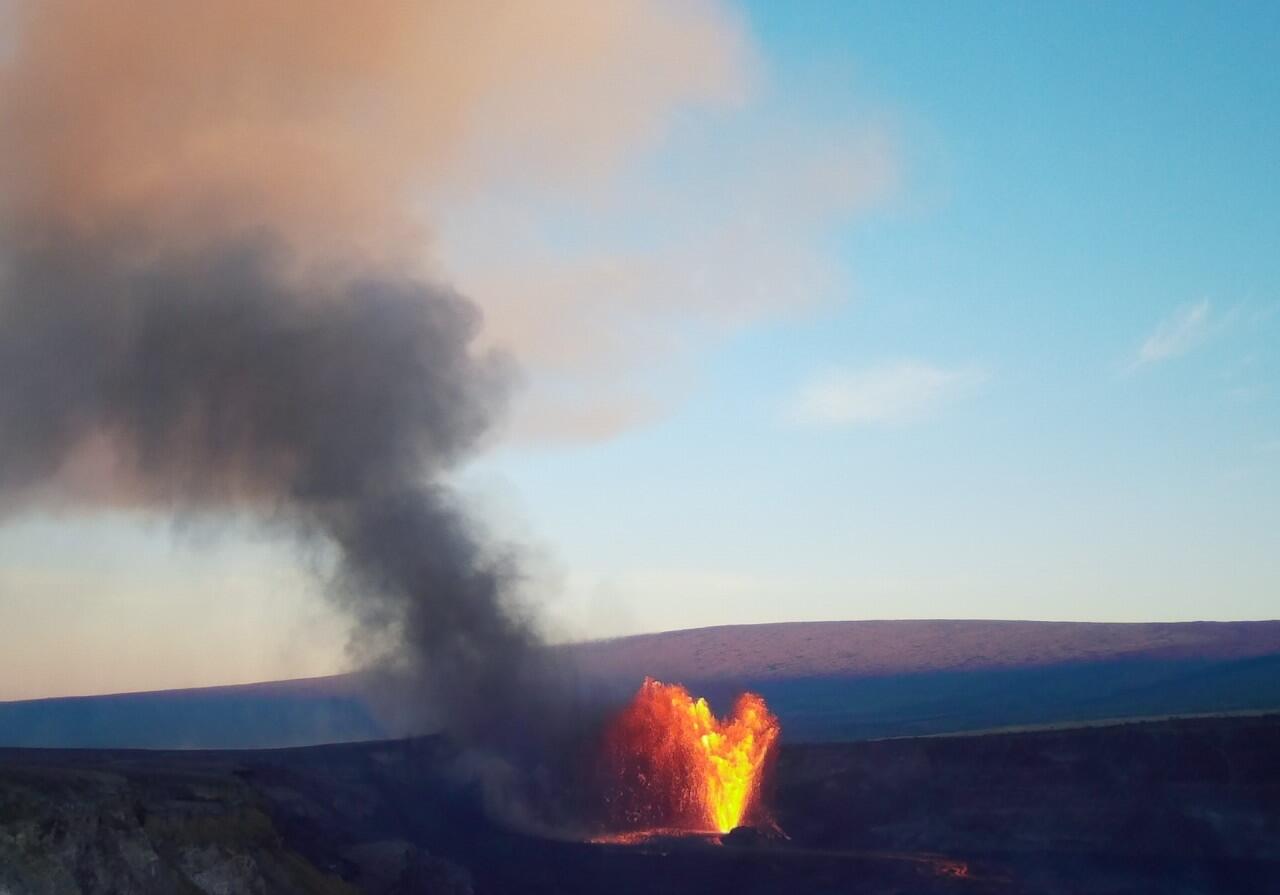Color photograph of volcanic plume from eruption with mountain in the background