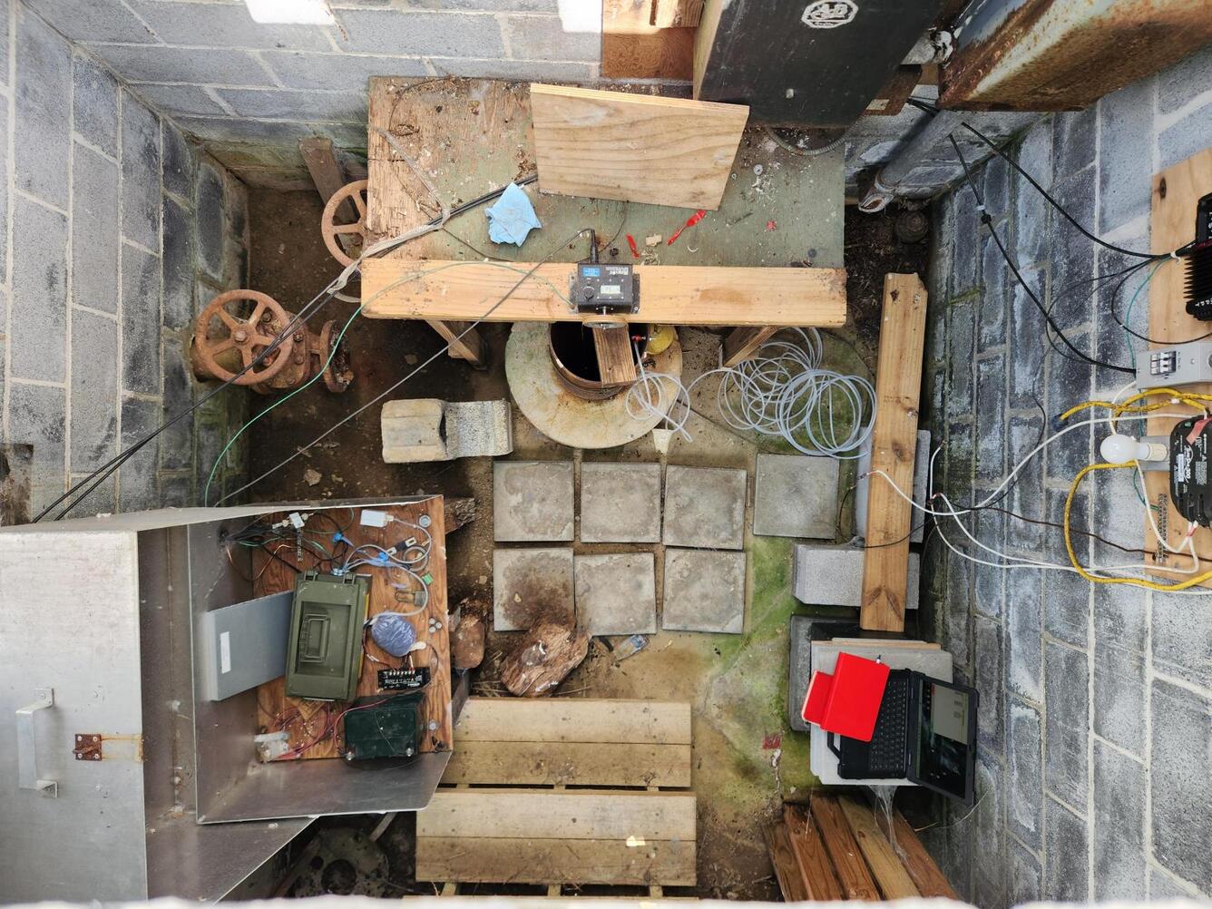 Top-down view of the inside of a wellhouse with observation well and monitoring equipment