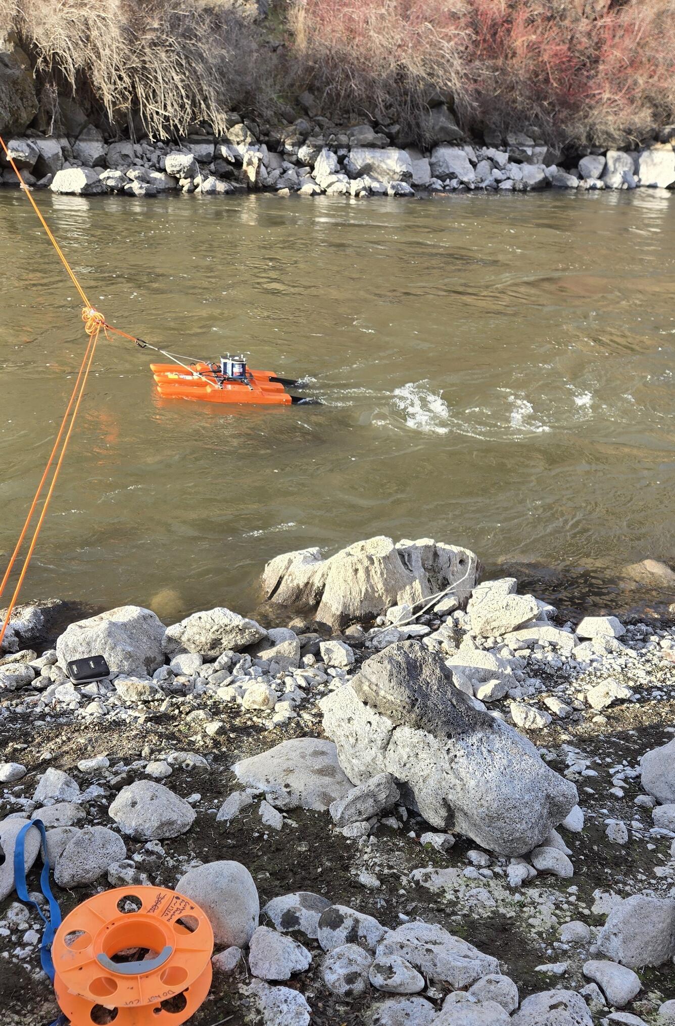 an orange trimaran boat on a tether