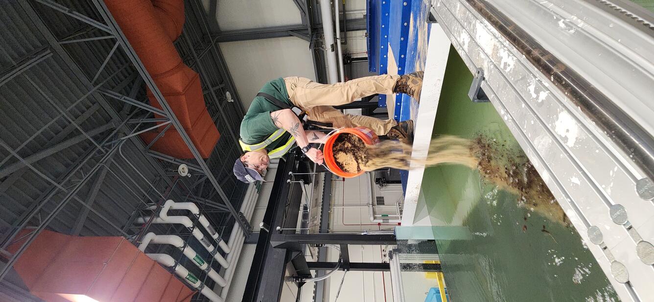 A Physical Scientist introducing sediment into the HIF tilting flume.