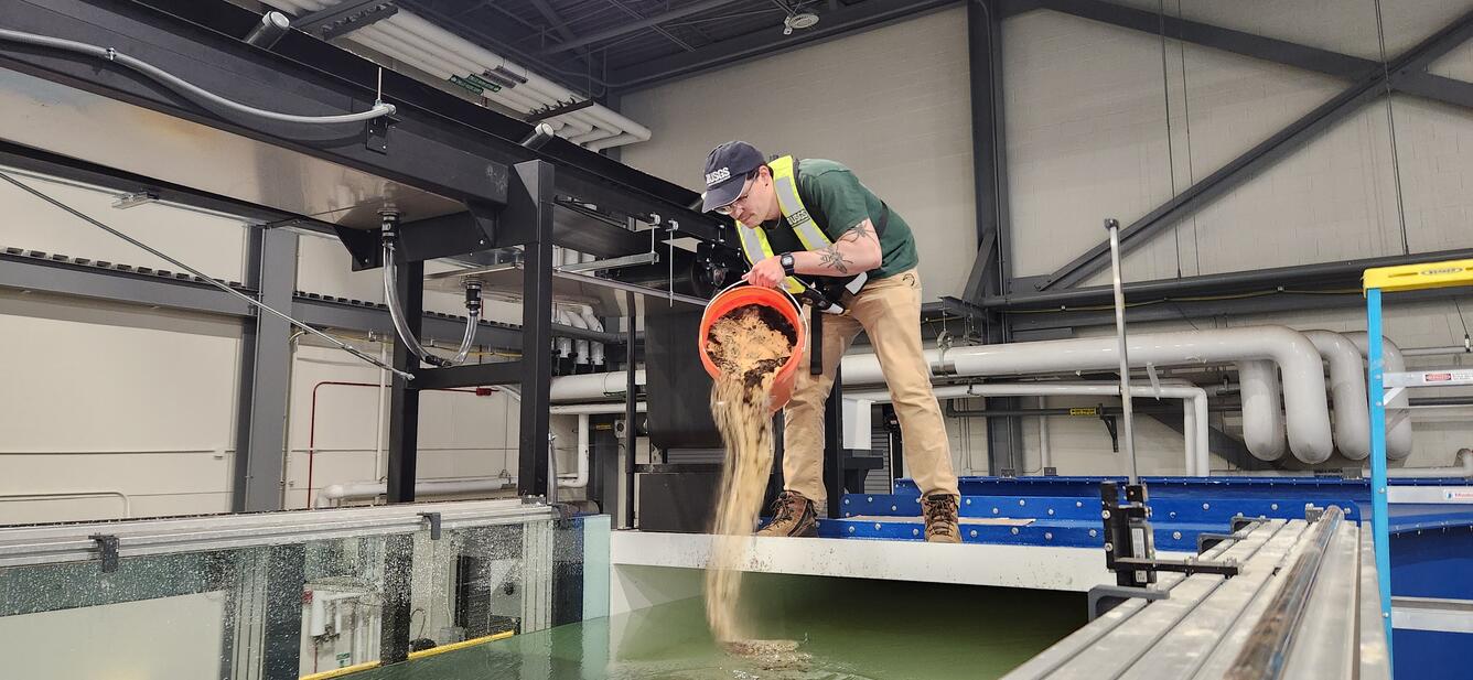 A Physical Scientist introducing sediment into the HIF tilting flume.