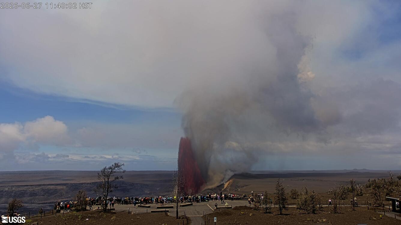 Color photograph of lava fountain erupting with visitors viewing in the foreground