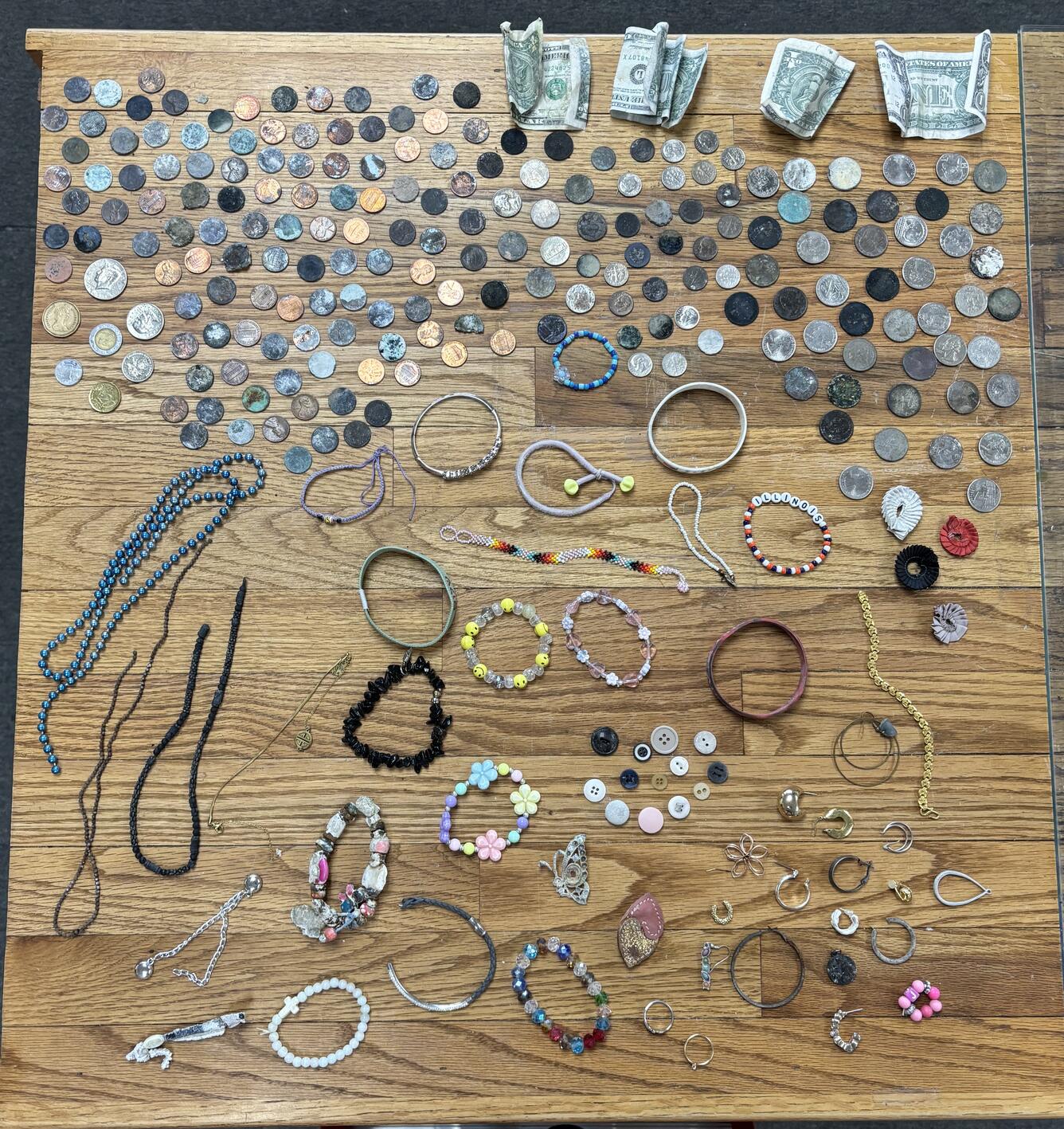 Coins, hair ties, and assorted jewelry laid out on a wooden table
