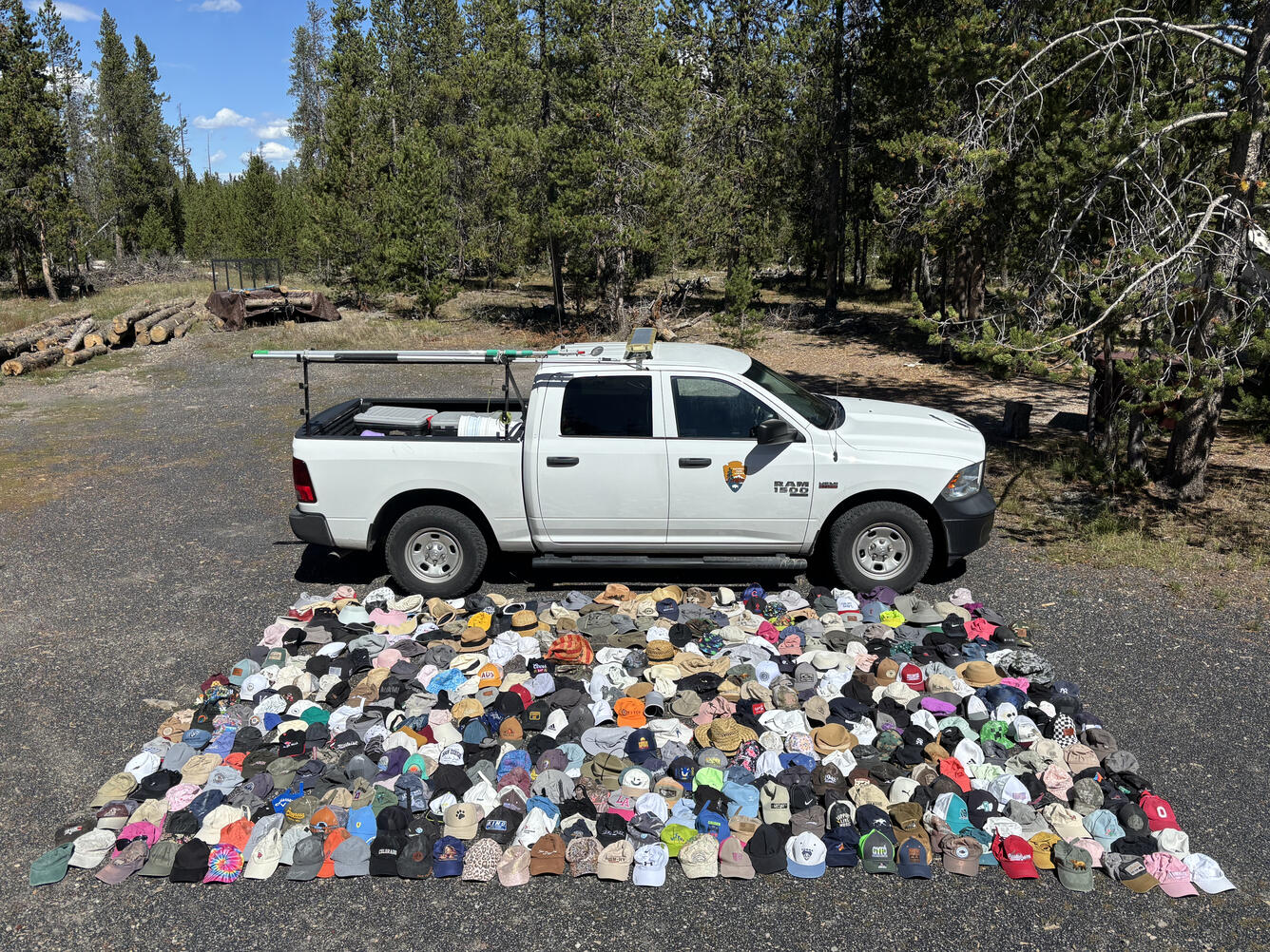 A white pickup truck is parked in front of an array of hundreds of hats of various colors laid out on the ground