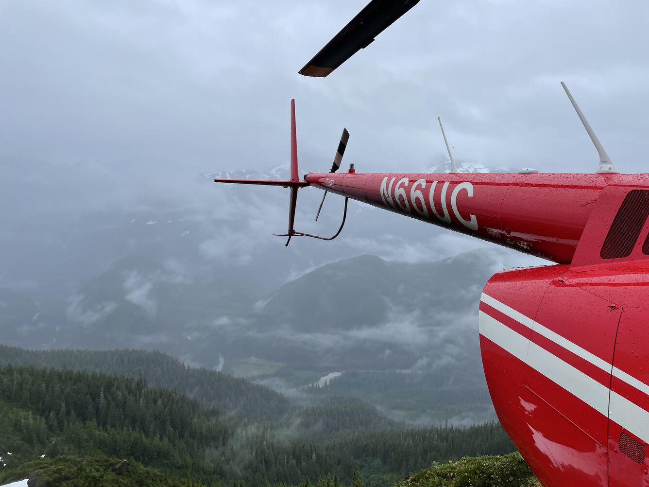 View of fog and clouds in the Aaron Creek valley with tail of R66 helicopter in right foreground.