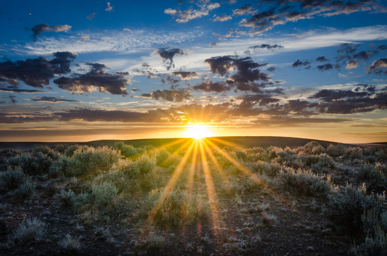 partly cloudy subset over a flat sagebrush landscape