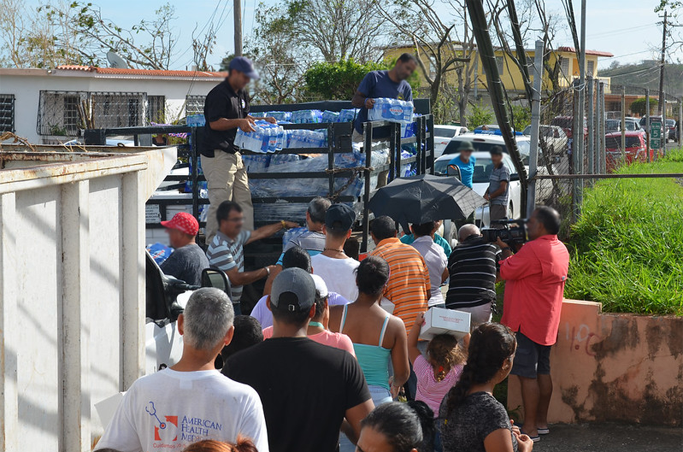 Community members in Puerto Rico line up to receive water from a disaster relief team after Hurricane María.