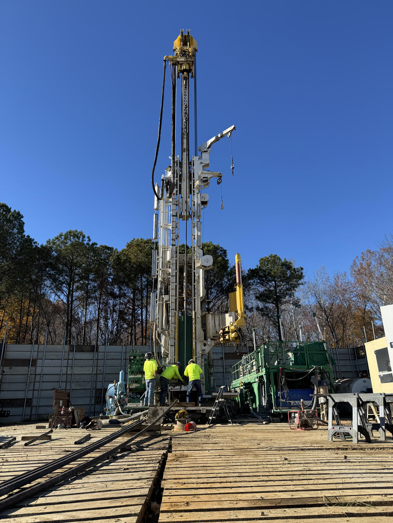 Drill rig lowering extensometer pipe into a borehole.