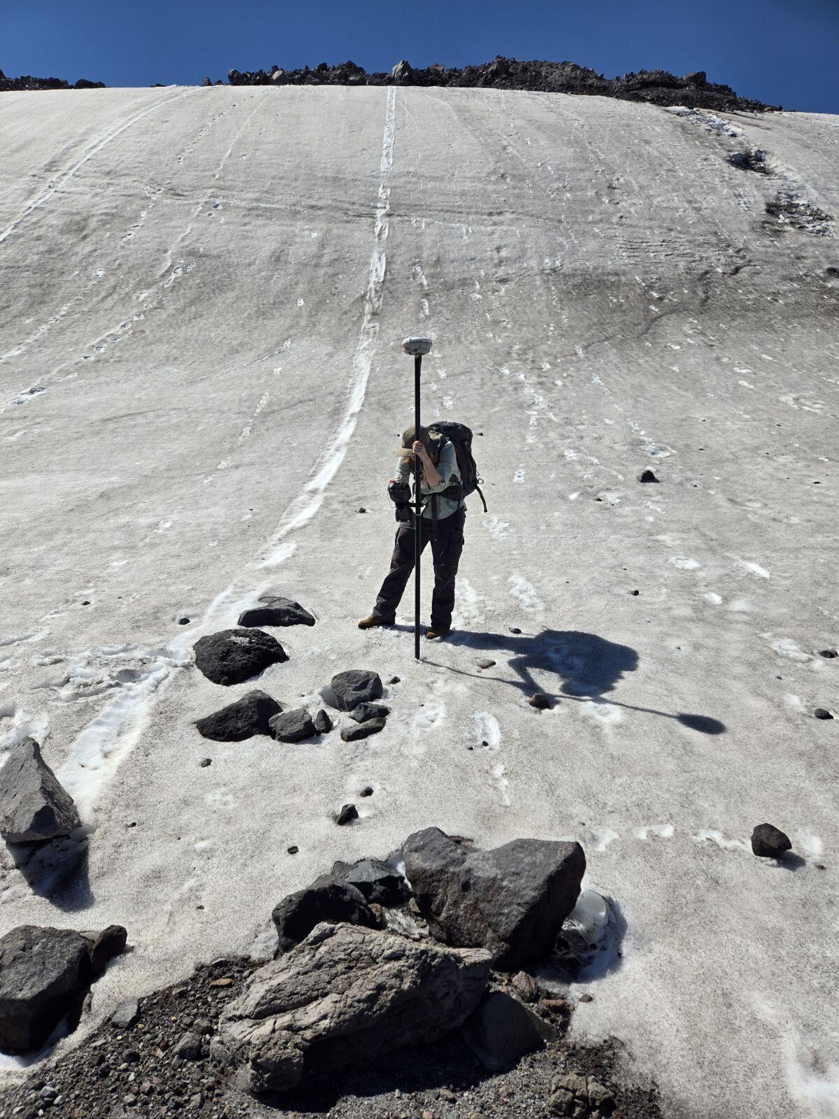 Erin Lysne using a GPS unit to measure the advancing front of Crater Glacier at Mount St. Helens in June of 2024.   