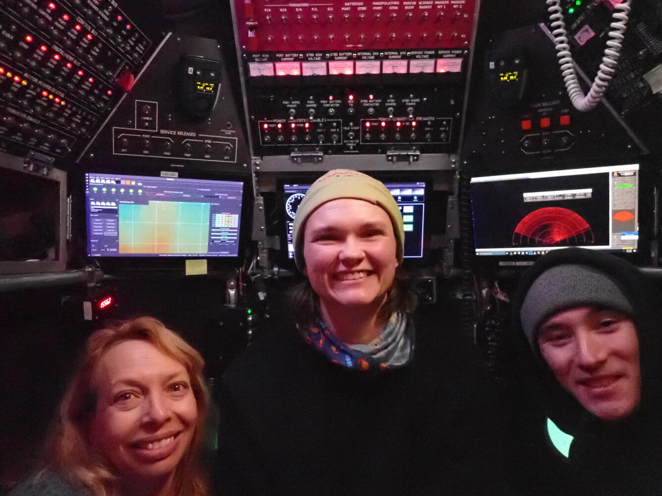 Three people in a submersible smile towards the camera