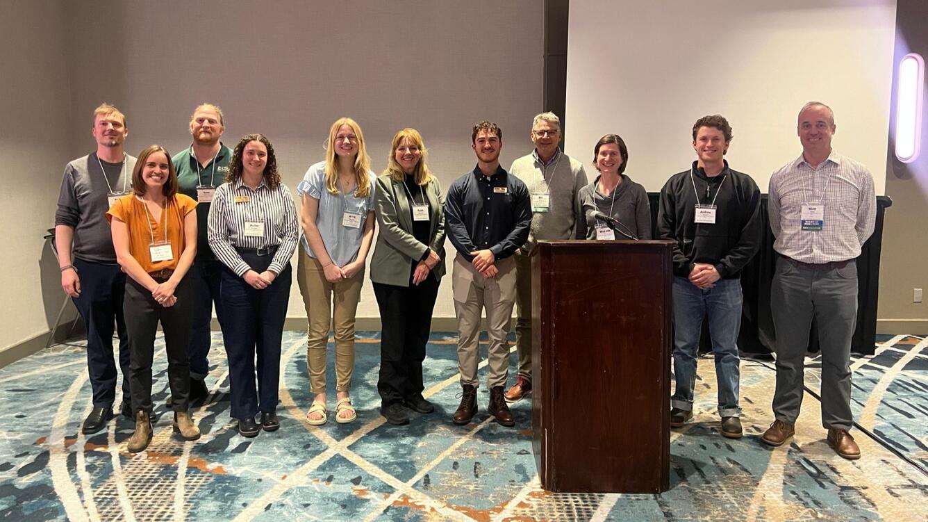 Eleven people at a conference standing in a line smiling for the camera