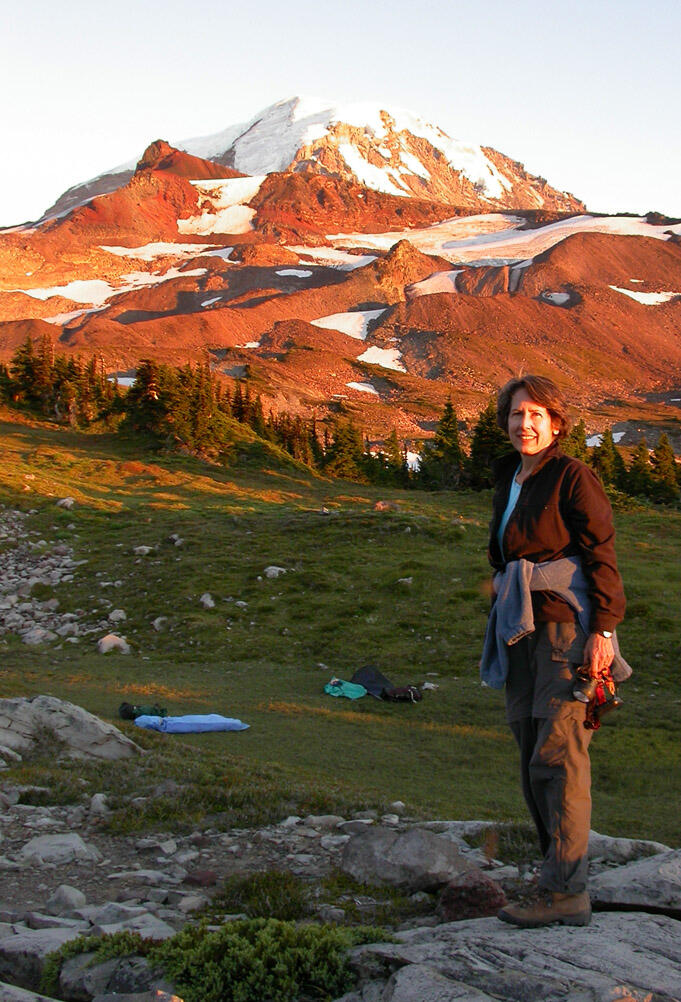 Andrea Woodward standing on a rock with Mt Rainier in the background