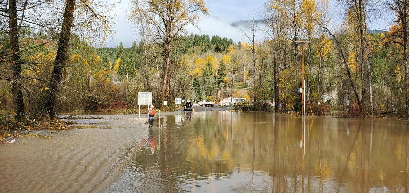 A technician measures shallow water across a roadway