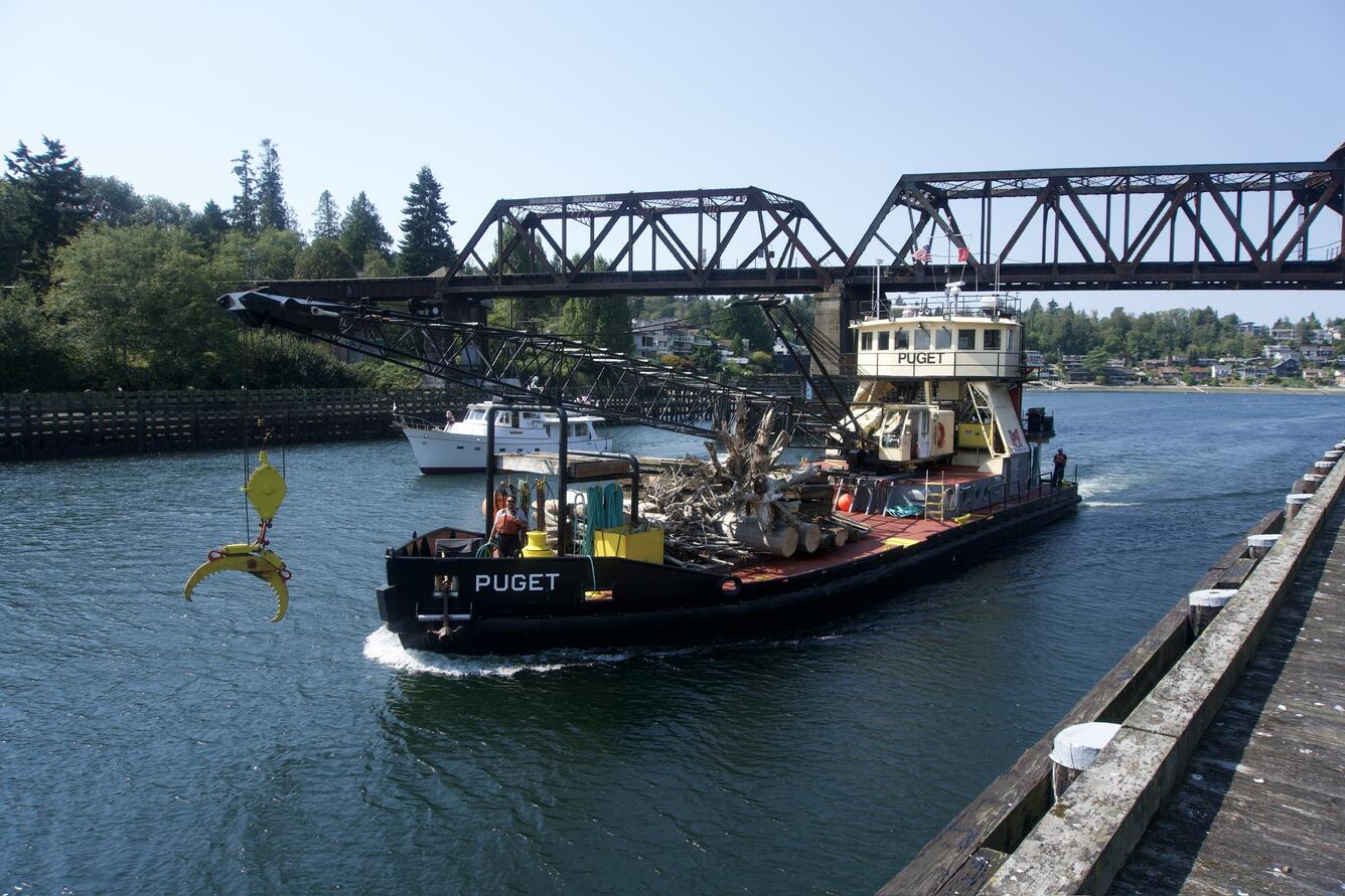 boat with onboard crane goes through the blue canal waterway on a clear sky day