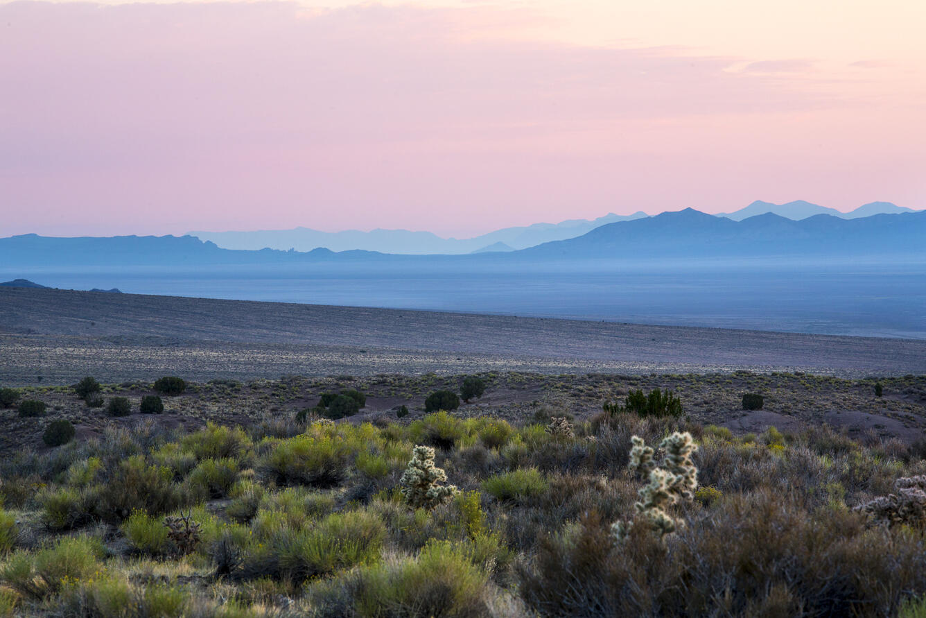 Photo of sunset with mountains and sagebrush in the foreground