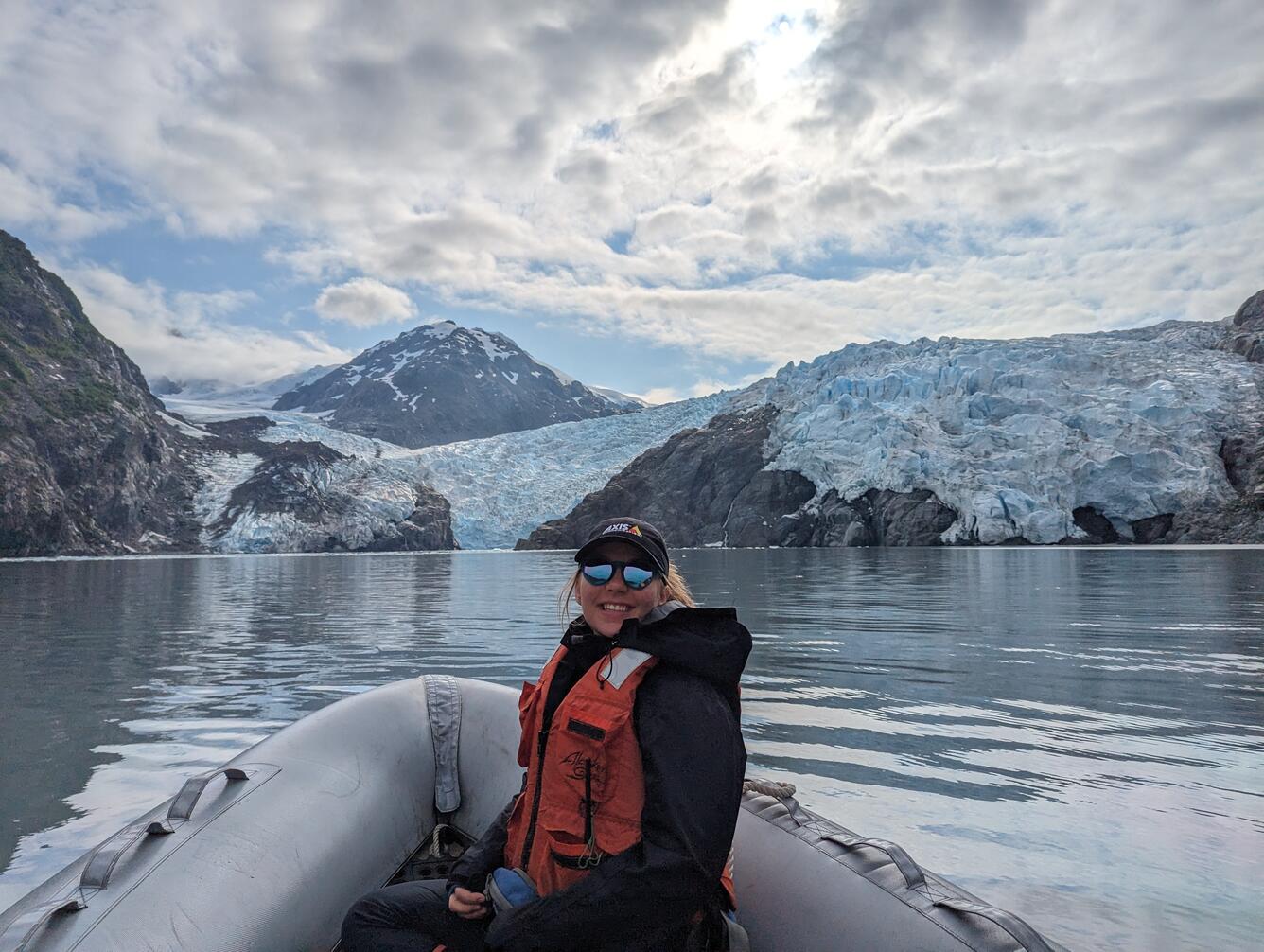 Person sitting on boat in front glacier