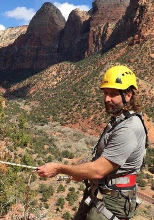 Person wearing helmet and harness in front of rock formations