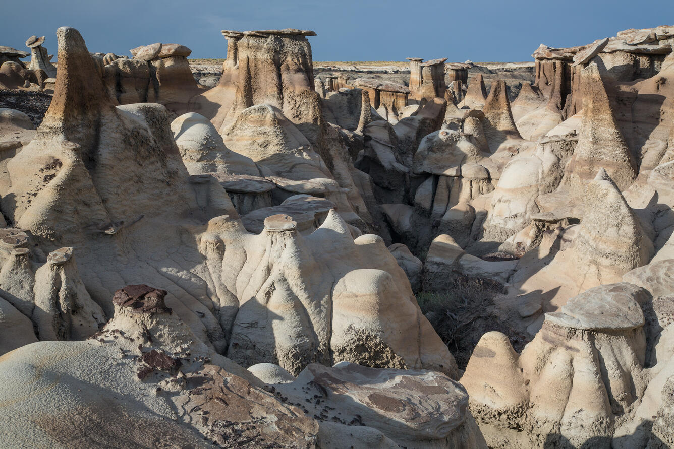 white and tan rocks jut out of the ground in pillars, against a blue sky