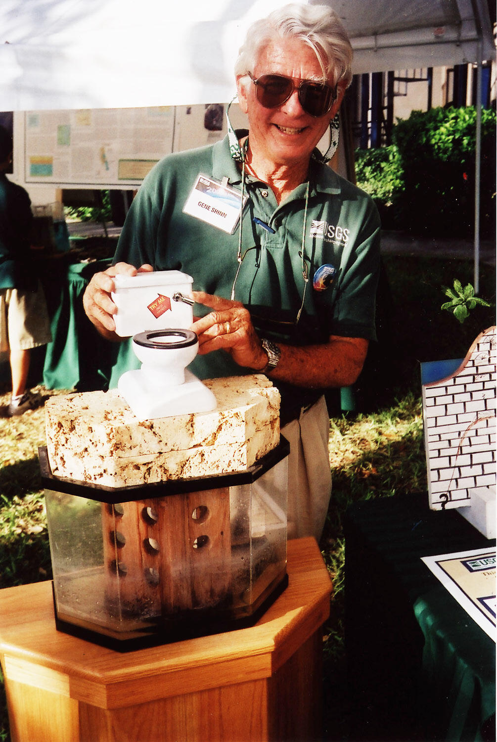 A man stands in back of an object, while smiling.