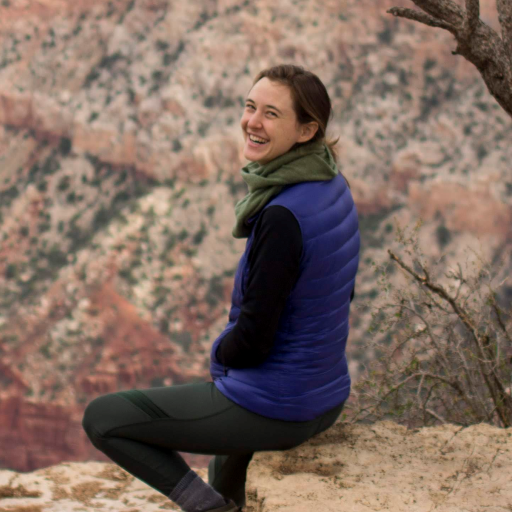 Person sitting near tree and in front of rock