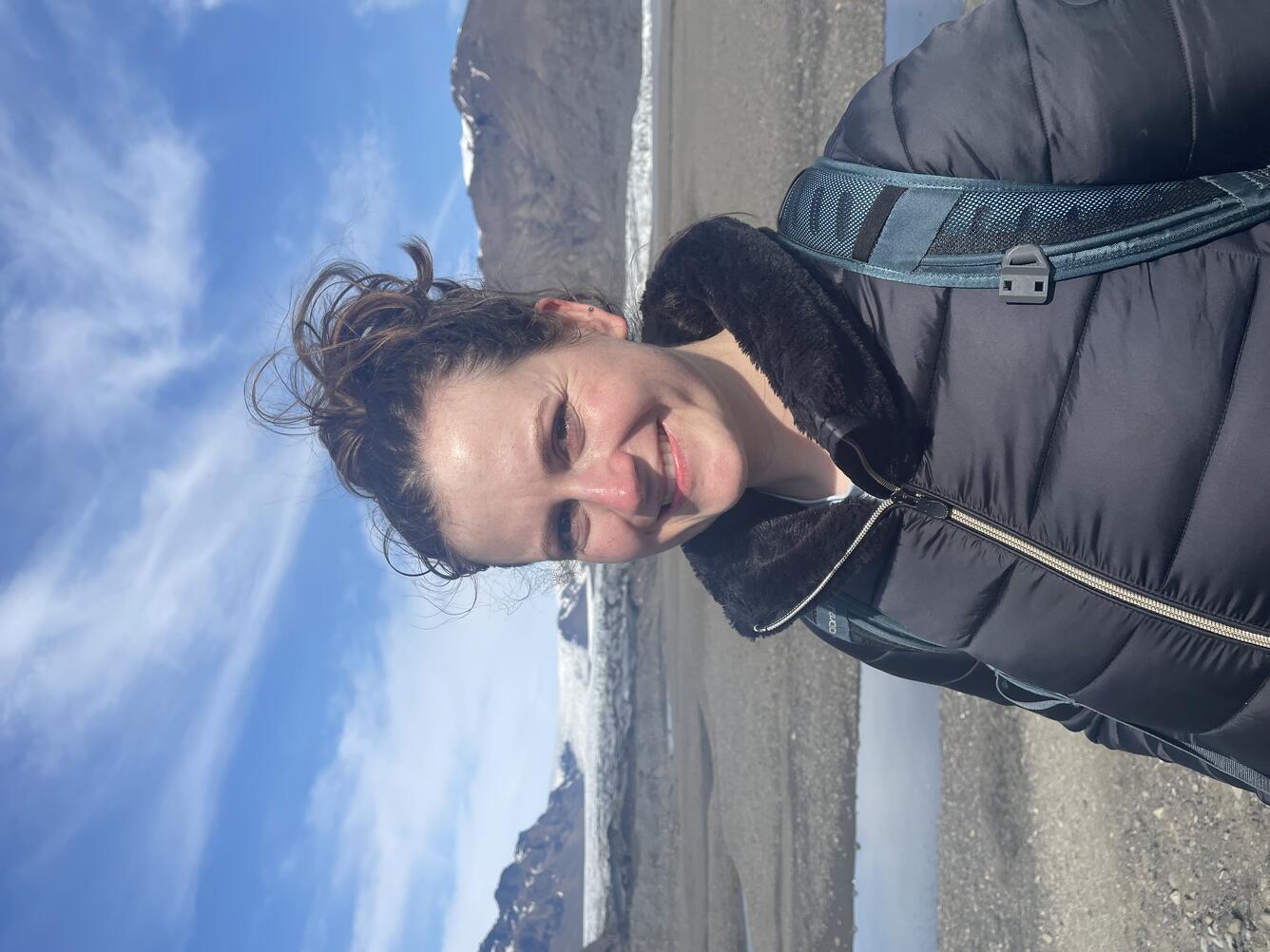 Woman smiling against rocky Icelandic background with mountains and snow