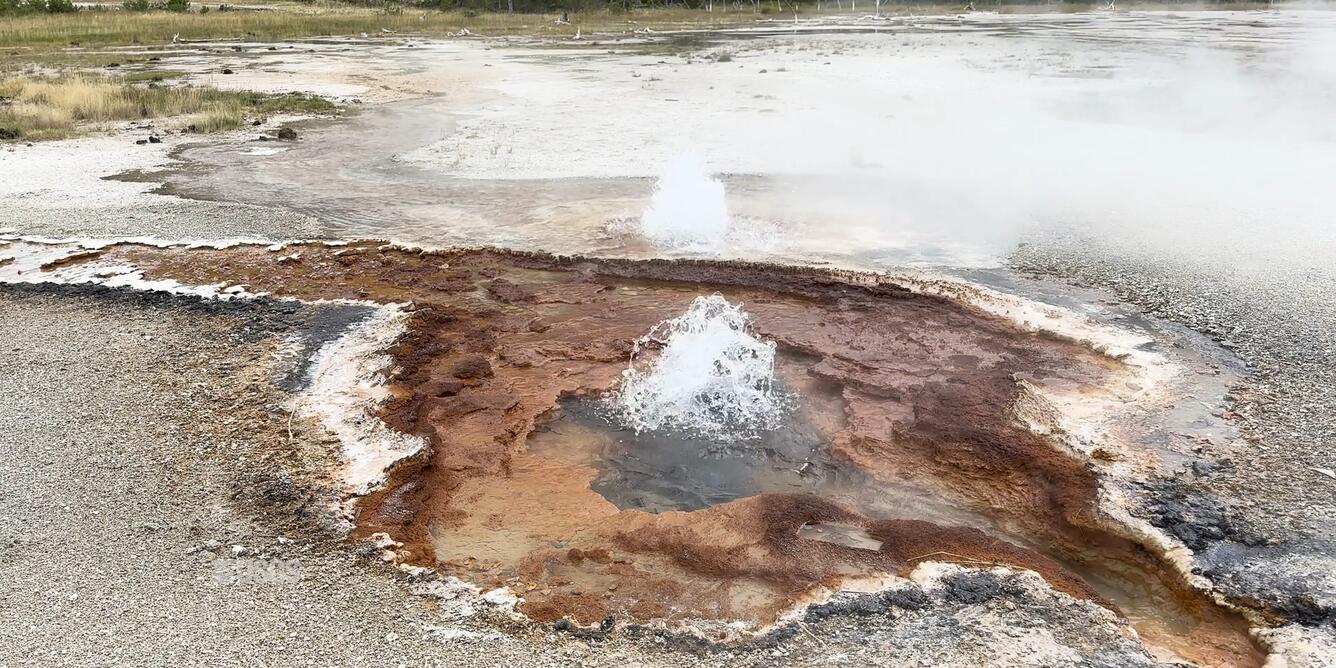 Bubbling water coming from the center of a small brownish and orange-colored hole