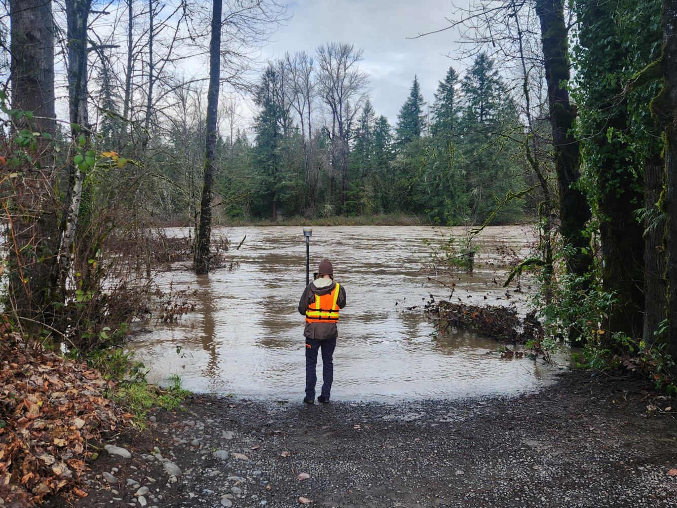 Scientist stands at the water's edge of the flooded boat ramp.