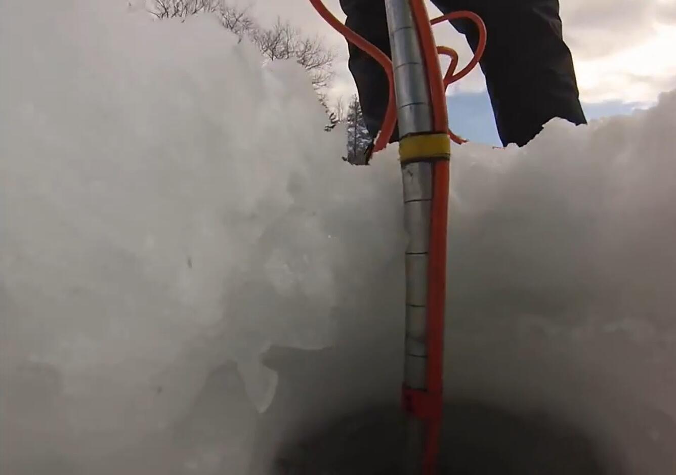 Looking at a person's legs as they lower a scientific probe down through a hole in the ice to the water below