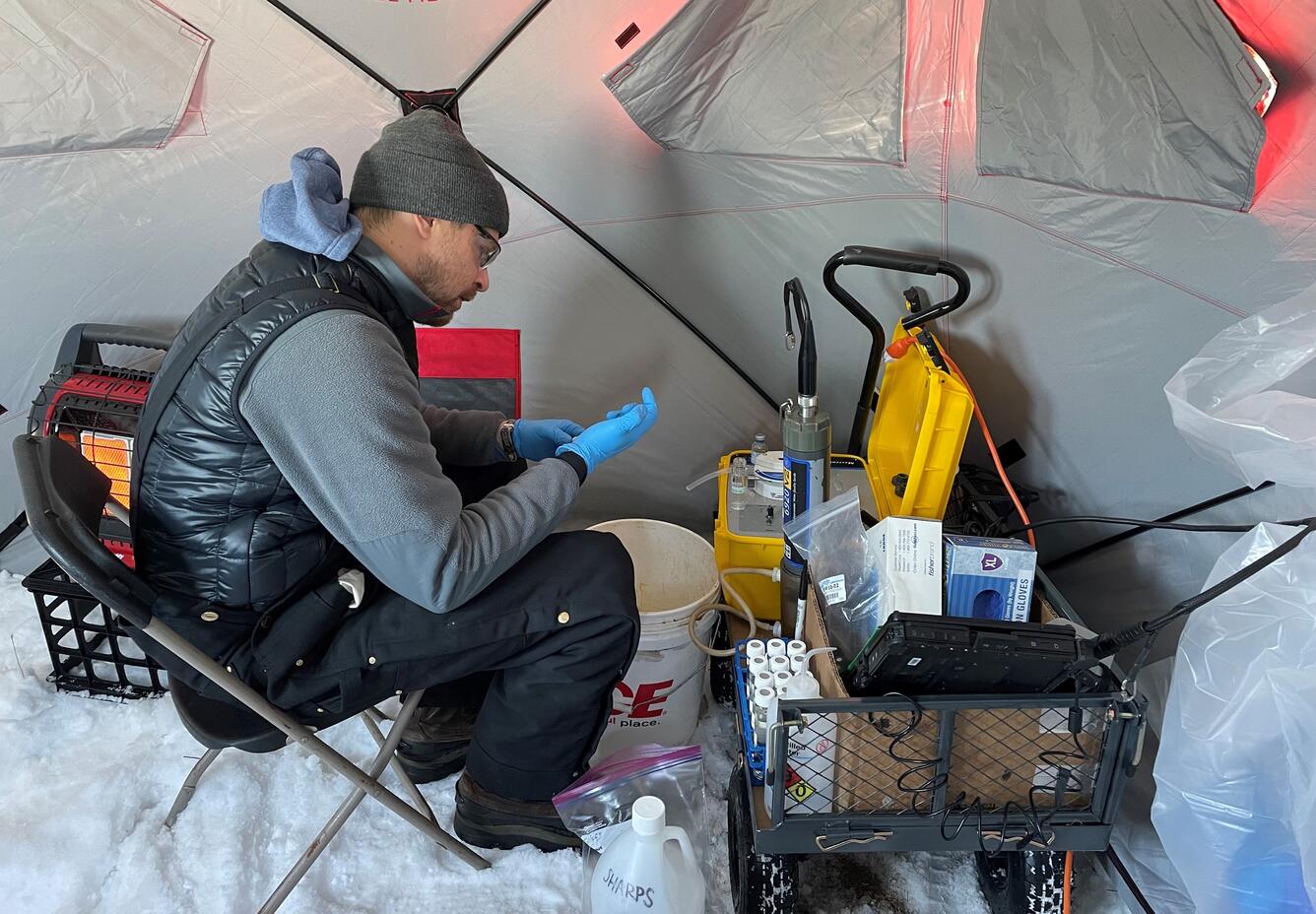 Man in tent on snowy ground sampling groundwater