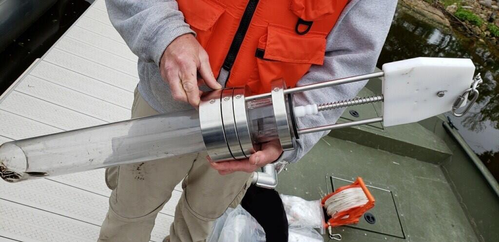 Scientist holds a transparent tube sediment corer device