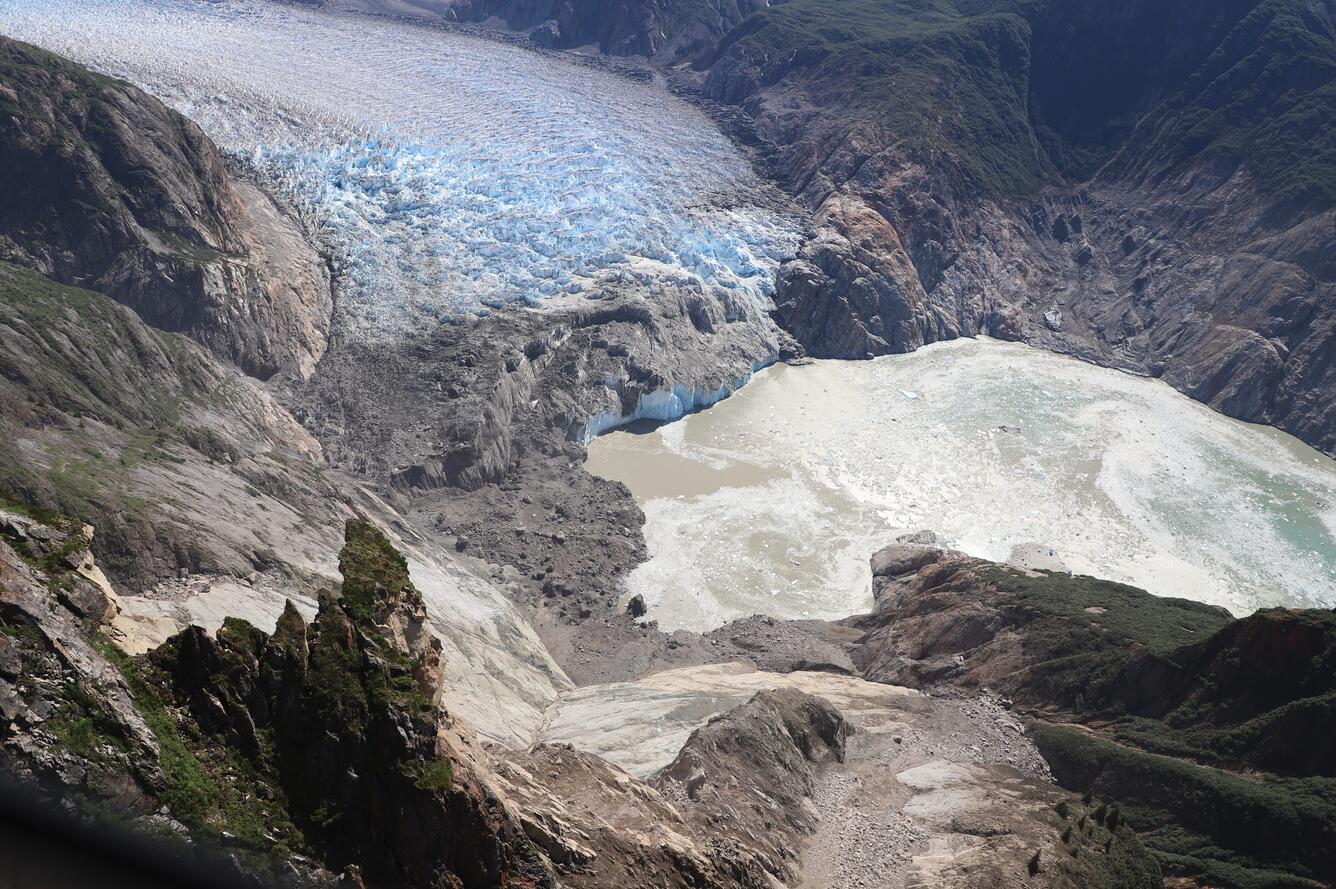 Aerial photo looking down a mountainside with the landslide in the foreground and glacier in the background