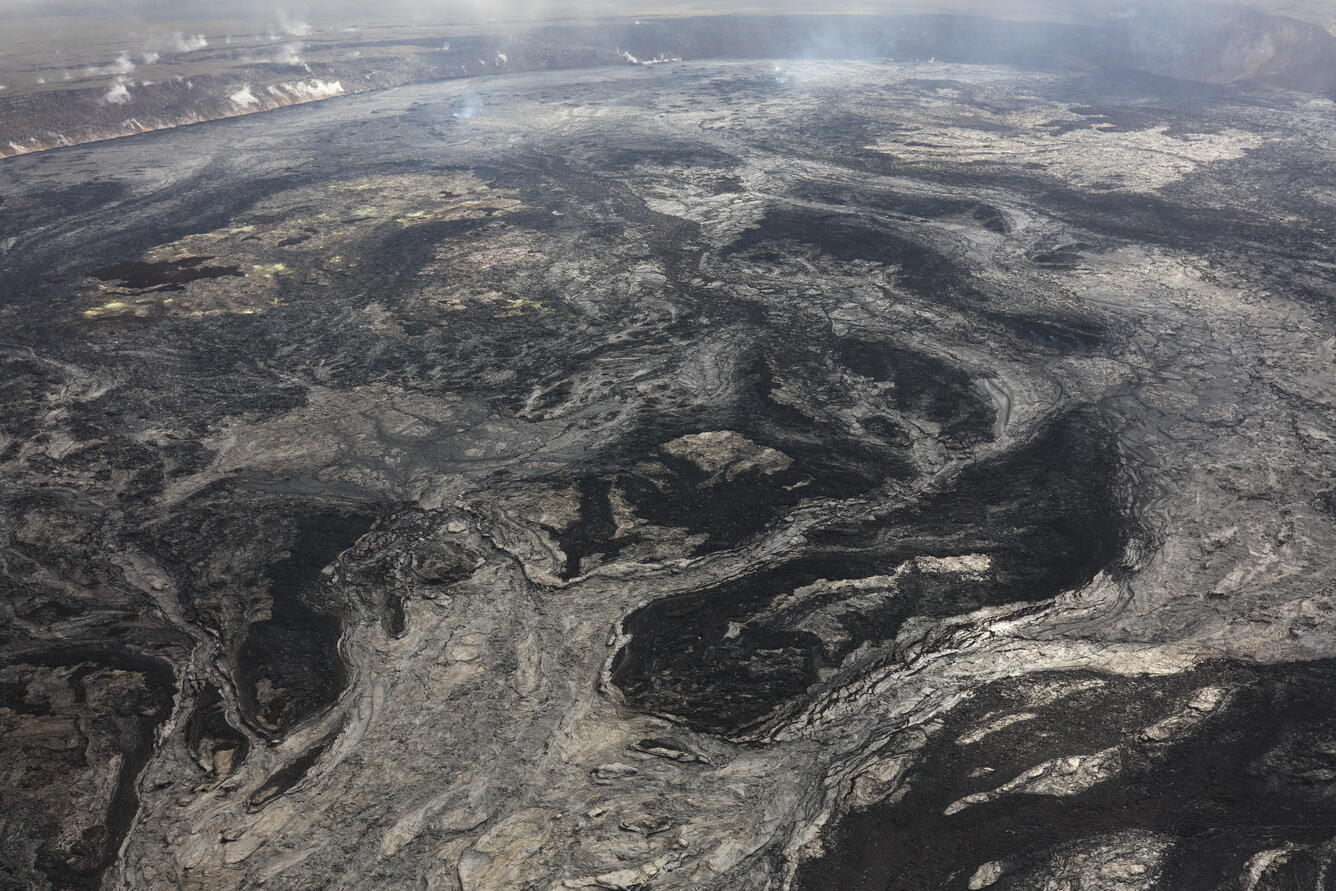 Black and light gray lava flows cover a volcanic crater floor