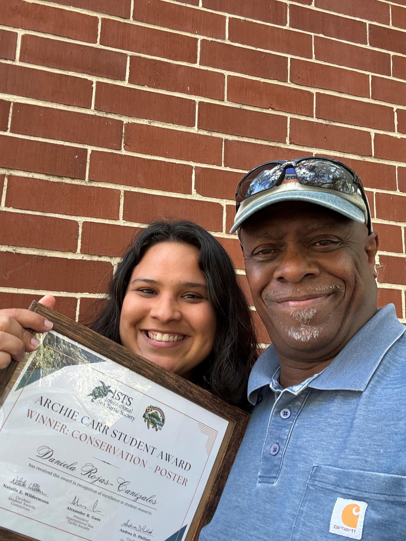 Two people are holding an award